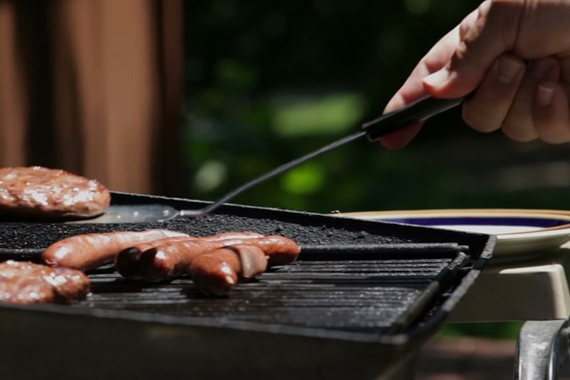 Grilling hot dogs outside.