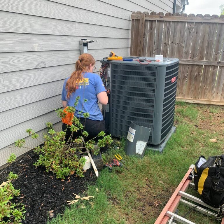 Joni at Absolute Climate Control performing maintenance on an outdoor unit.